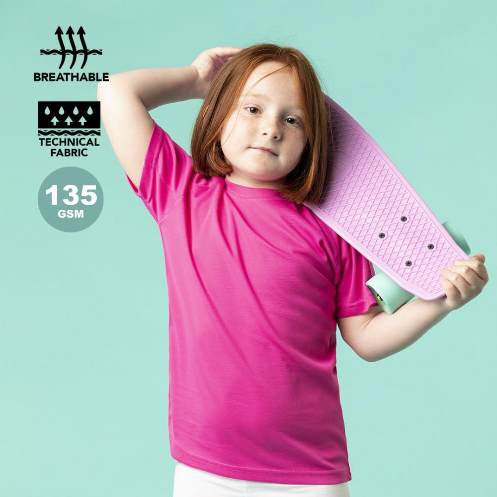 A child in a bright pink shirt holds a pink skateboard against a teal background. The shirt features a logo. Tecnic Plus - Image 1