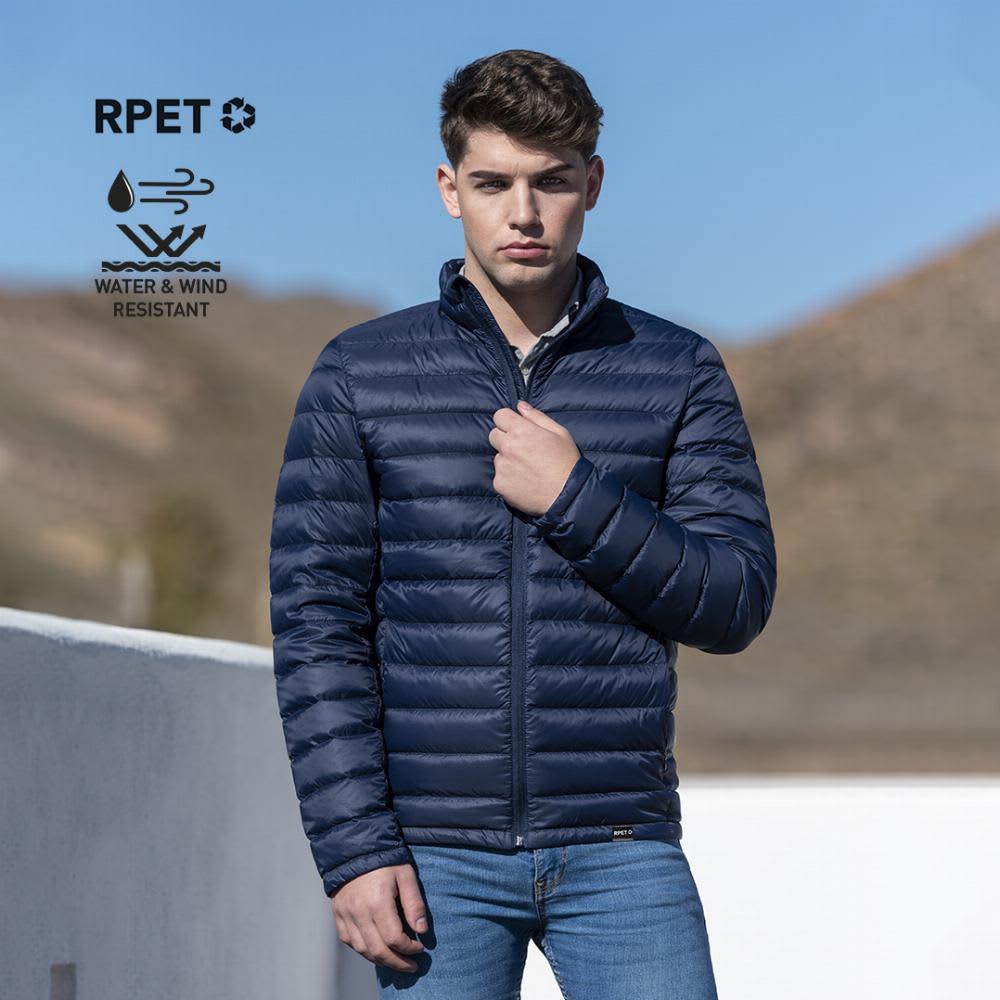 A navy blue puffer jacket worn by a young man against an outdoor backdrop. The jacket features a logo. Mitens - Image 1