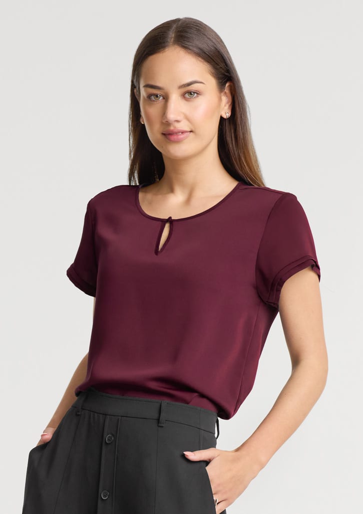 A maroon women's short sleeve blouse with a keyhole detail at the neckline, paired with black trousers. Womens Evelyn Short Sleeve Blouse - Image 1