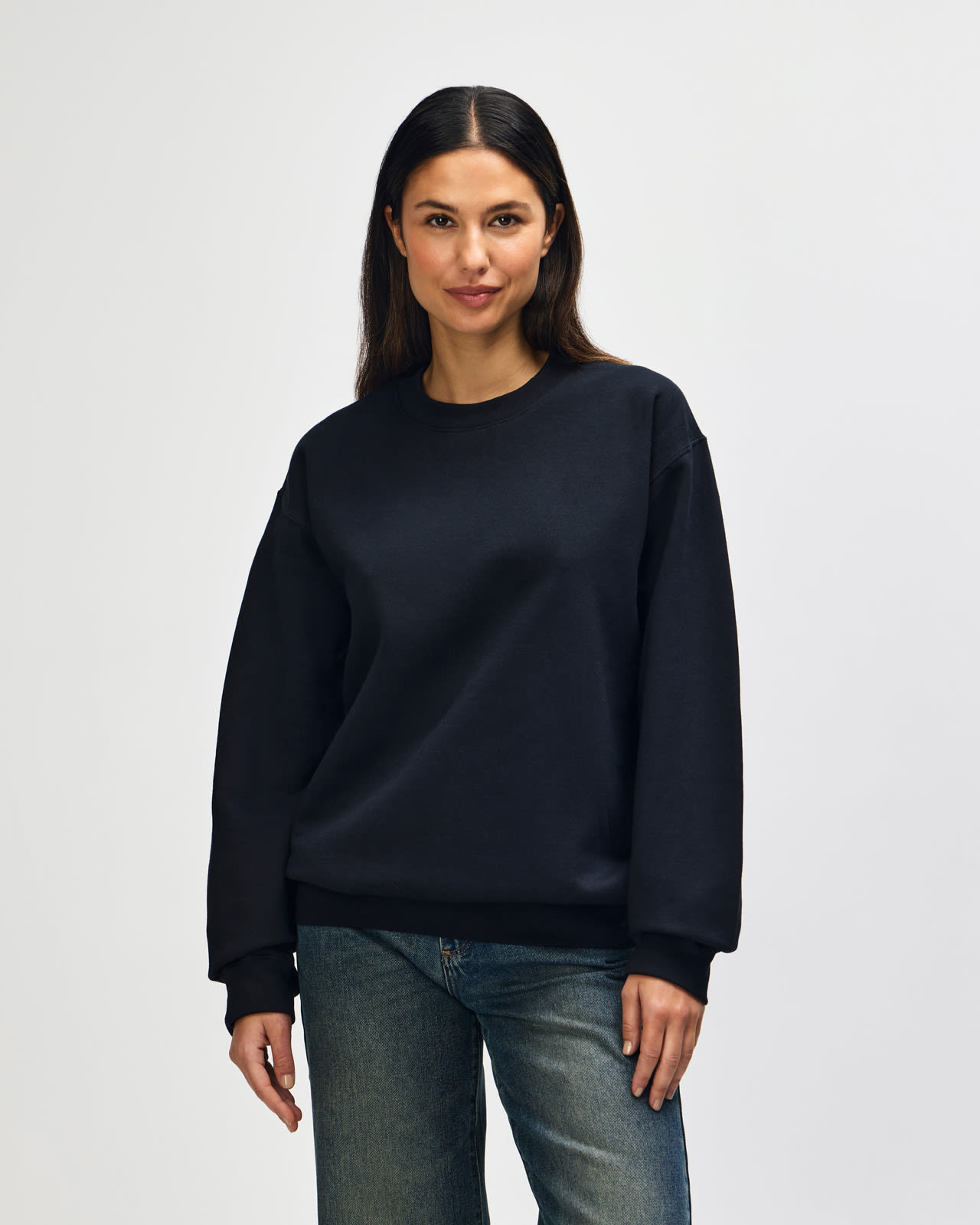 A black Gildan Softstyle adult sweatshirt being worn by a male model. The sweatshirt features a simple design and has a logo. Gildan Softstyle Adult Sweatshirt - Image 1