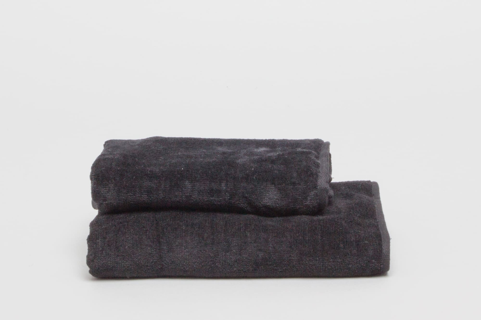A black sports towel set stacked on a white background, featuring a soft texture. The towels have a branding logo. Signature Sports Towel 380 gsm Black - Image 1