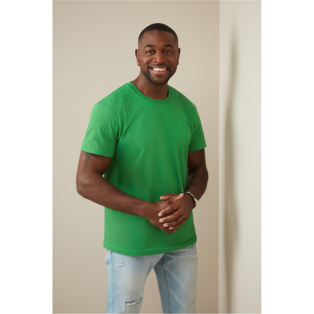 Men's heavyweight green crew neck T-shirt displayed by a smiling man, featuring a logo on the shirt. Men's Heavyweight Comfort-T Crew Neck - Image 1