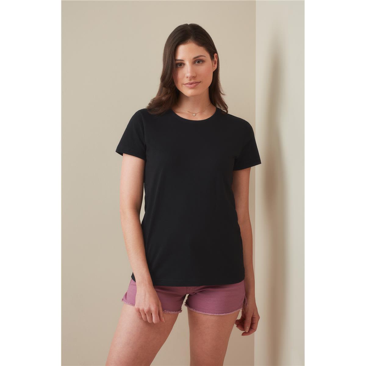 A black women's heavyweight comfort T-shirt displayed on a model, paired with pink shorts. The shirt has a simple design and a logo. Women's Heavyweight Comfort-T Crew Neck - Image 1