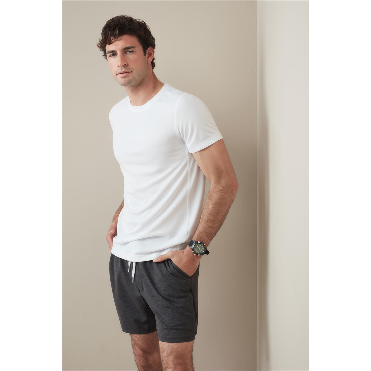 A white crew neck t-shirt displayed on a model, paired with grey shorts. The shirt features a logo. Men's Active 140 Crew Neck - Image 1