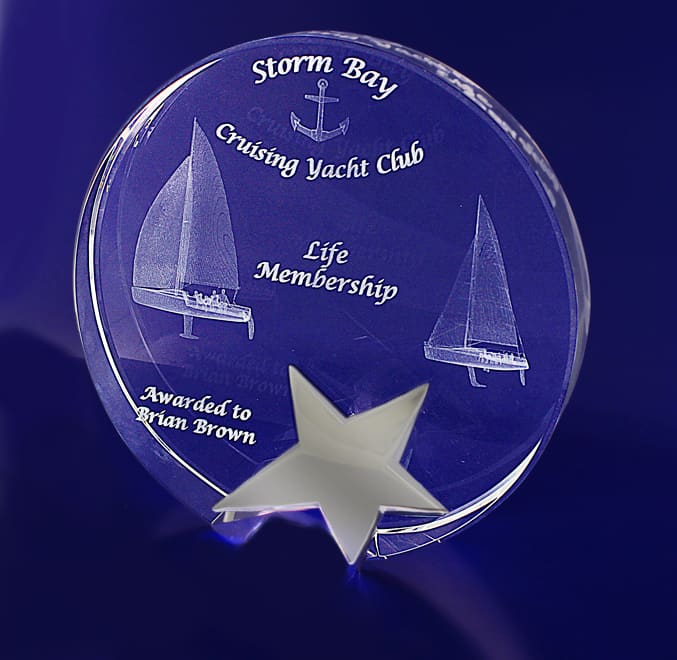 A 3D crystal star award in a round shape, featuring a sailboat design and engraved text, displayed on a blue background. 3D Crystal Star Round (150mm) - Image 1