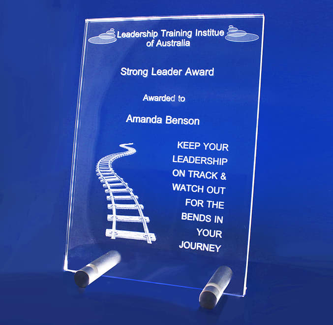 A clear acrylic plaque featuring a train track design with a stand. It has a logo and award text. 3D Crystal A4 Studio Plaque - Image 1