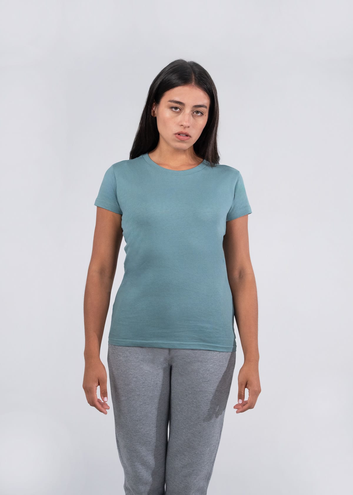 A fitted women's T-shirt in a soft teal colour displayed on a model, paired with grey sweatpants. The shirt features a logo. Women's Earth Care T-shirt - Image 1