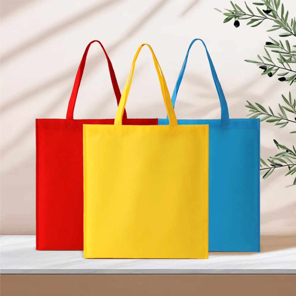A set of three tote bags in red, yellow, and blue with handles, displayed on a surface with a minimal background. Newtown pp non woven tote bag - Image 1
