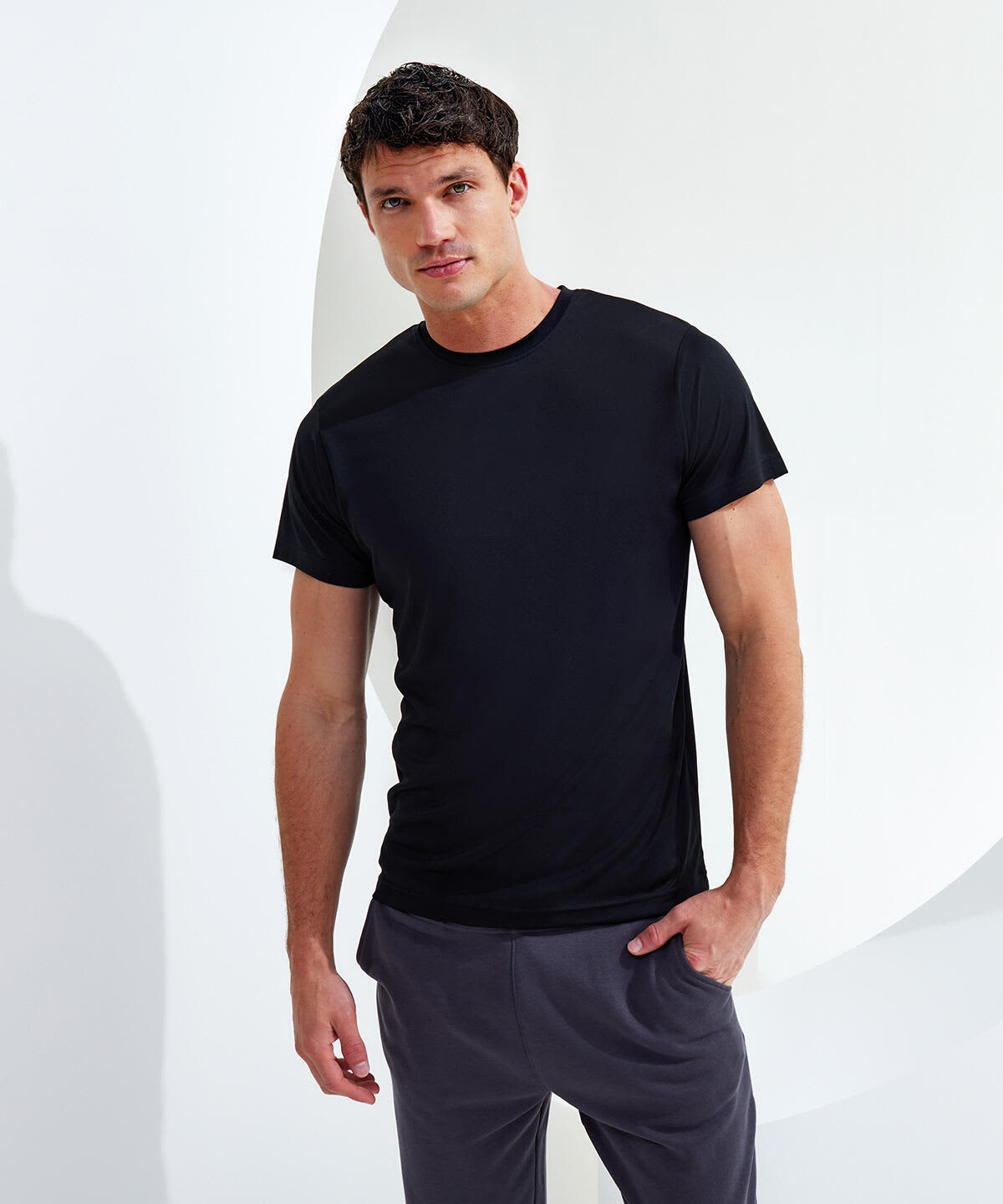 A black performance t-shirt displayed on a male model against a minimalist backdrop, showcasing its fit and style. Performance T-Shirt - Image 1