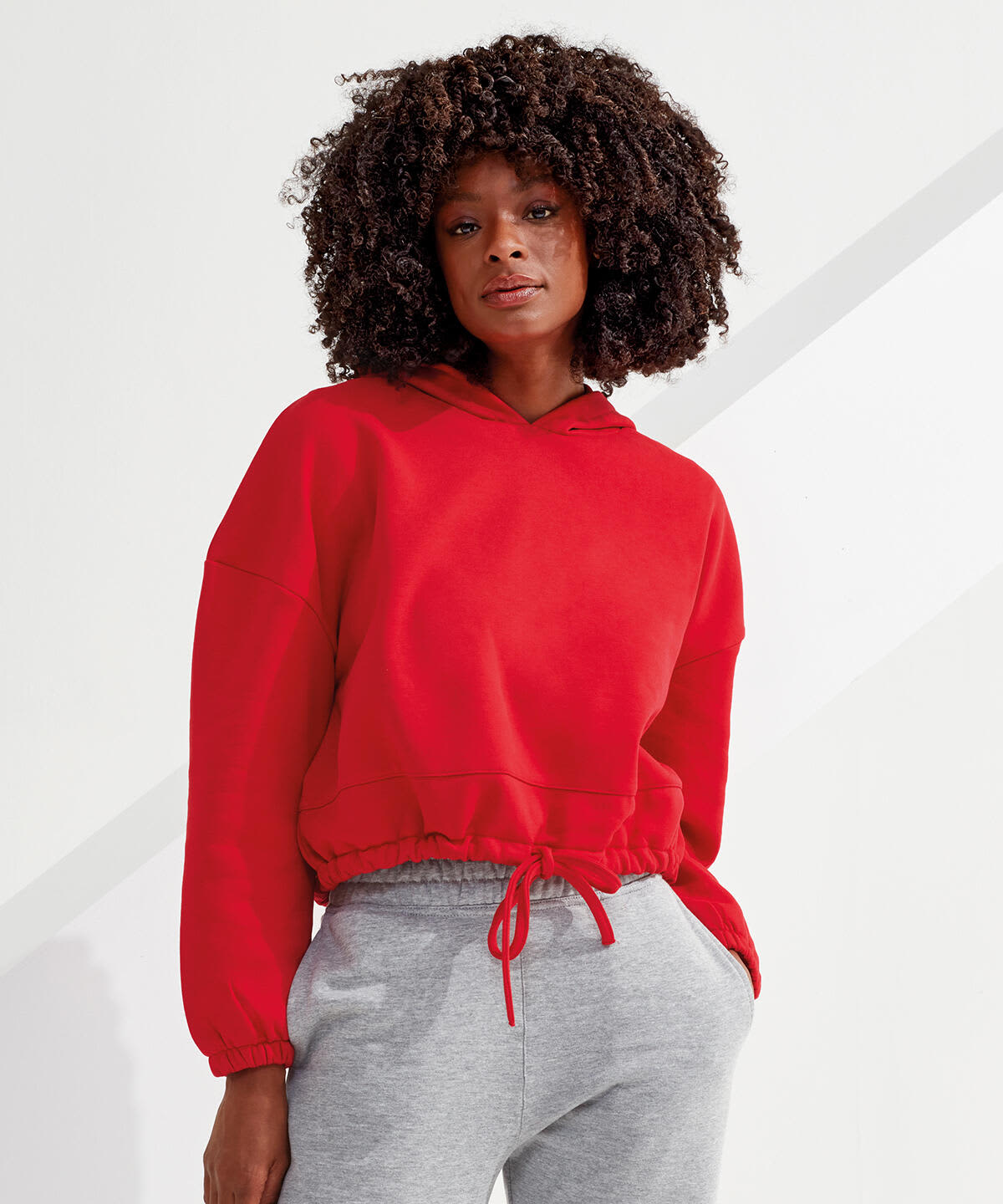 A red cropped oversize hoodie with a drawstring hood, paired with grey pants, featuring a logo on the fabric. Cropped Oversize Hoodie - Image 1