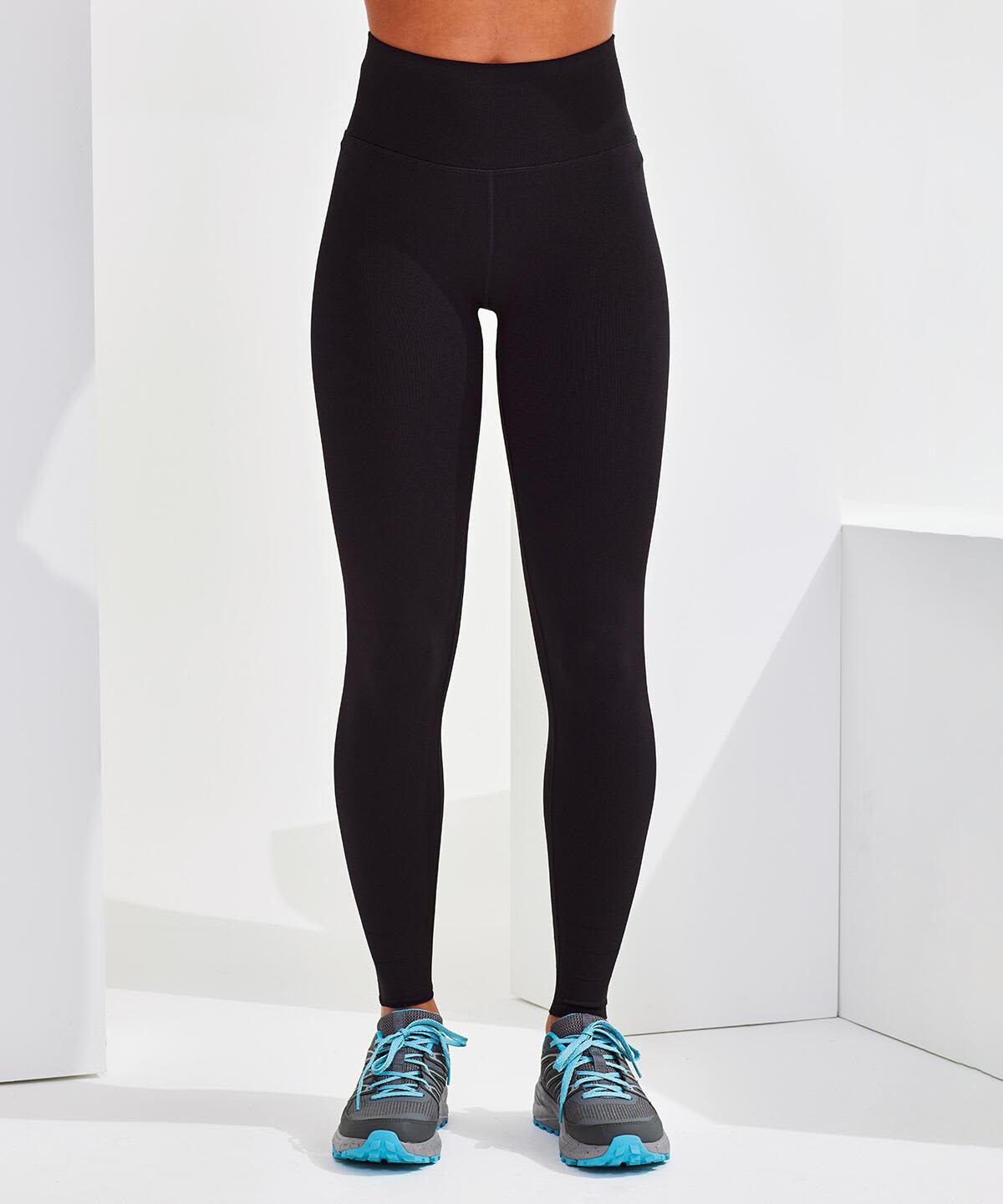 A pair of black seamless leggings displayed on a model, paired with grey and blue athletic shoes. Custom Length Seamless Leggings - Image 1