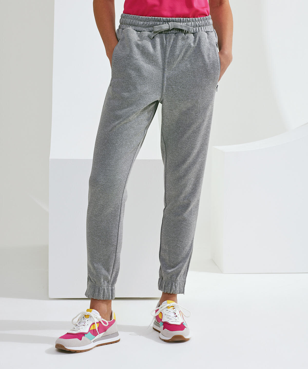 Grey joggers with an elastic waist and cuffs, featuring side pockets, worn with colourful athletic shoes. Spun Dyed Joggers - Image 1