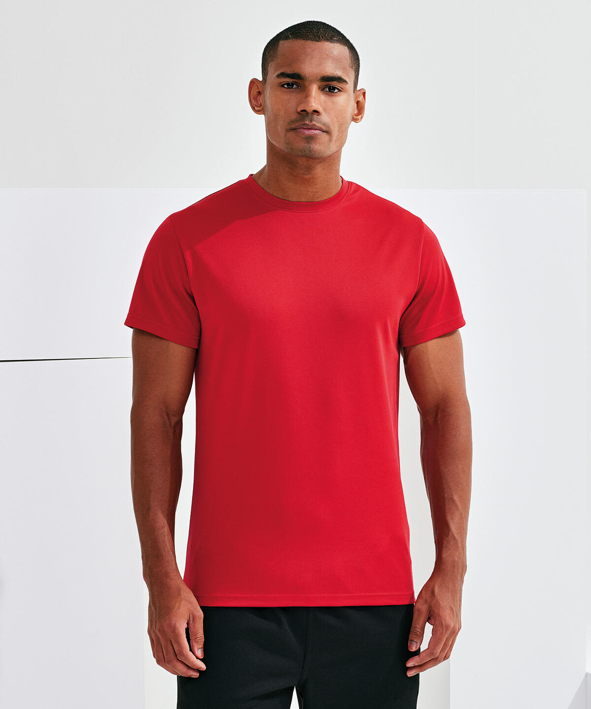 A red textured t-shirt is displayed, worn by a male model standing against a neutral background. Cationic Recycled Textured T-Shirt - Image 1