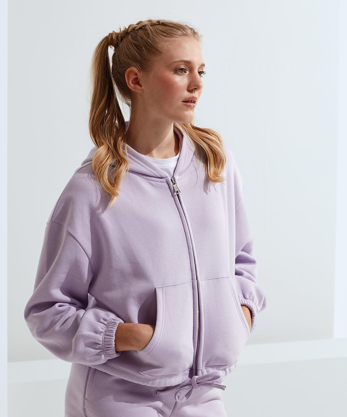 A lilac recycled drawstring full-zip hoodie with a zip front and side pockets worn by a model. Recycled Drawstring Full-Zip Hoodie - Image 1