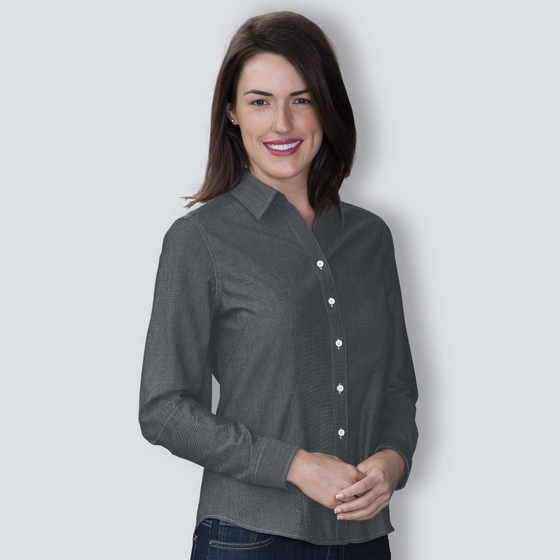 A woman wearing a dark grey button-up chambray shirt with a collar and white buttons. The Montreal Chambray Shirt - Womens - Image 1