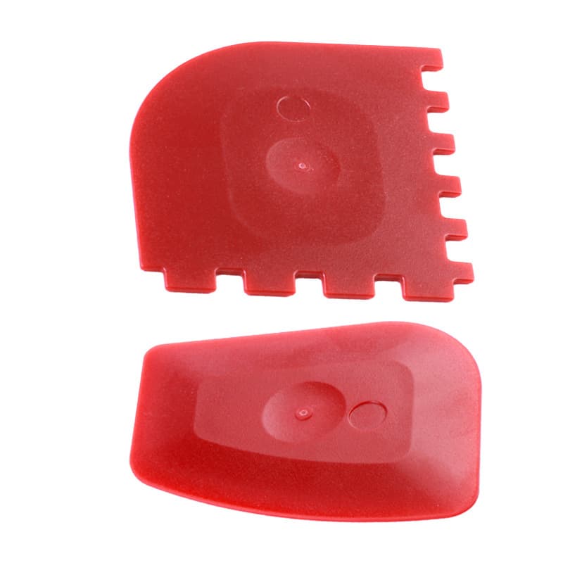Two red grill pan scrapers featuring smooth and serrated edges, designed for cleaning and maintenance. Durable Grill Pan Scrapers - Image 1