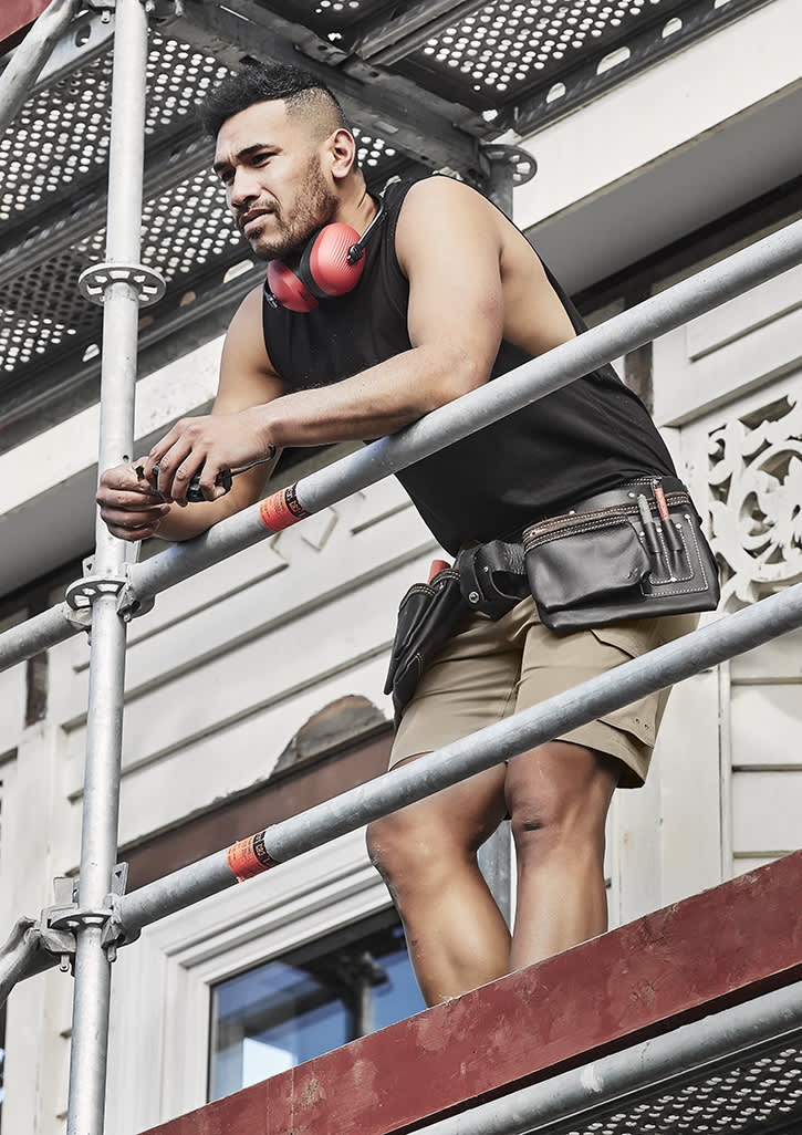 A man in a black sleeveless tee and shorts stands on scaffolding, wearing headphones and a tool belt. Mens Streetworx Sleeveless Tee - Image 1