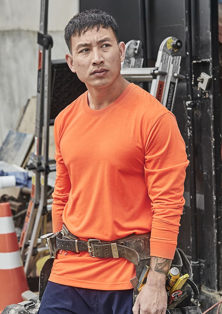 An orange long sleeve tee with a fitted design, suitable for safety wear, worn by a man on a construction site. Mens Hi Vis Long Sleeve Tee - Image 1