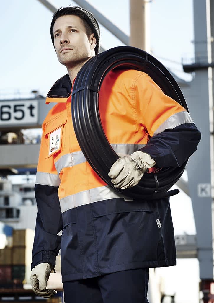 Men's hi-vis ultralite waterproof jacket in orange and navy, featuring reflective stripes and a logo. Model holds a coil of cable. Mens Hi Vis Ultralite Waterproof Jacket - Image 1