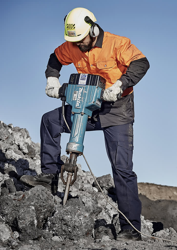 A man in an orange and black jacket and ear protection operates a blue jackhammer on rocky terrain. Mens Basic Cargo Pant (Regular) - Image 1