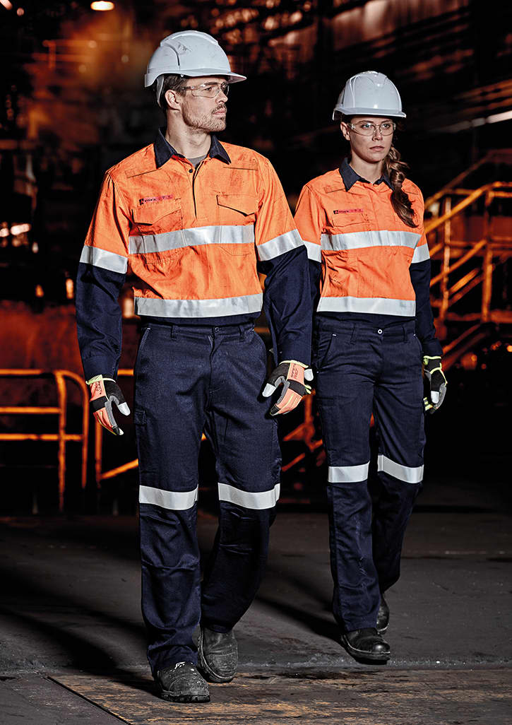 Two individuals wearing high-visibility orange shirts and navy cargo pants walk in an industrial setting, both wearing helmets and gloves. Womens Orange Flame Taped Cargo Pant - Image 1
