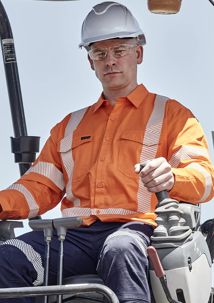 A man wearing an orange hi-vis shirt with segmented reflective tape operates machinery while wearing a white hard hat and safety glasses. Mens X Back NSW Rail Shirt – Segmented Tape - Image 1