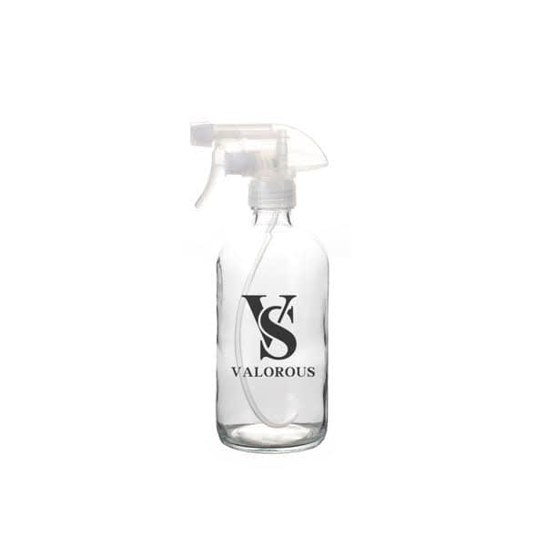 A clear glass spray bottle with a transparent nozzle, featuring a logo design. 17 oz. Clear Glass Spray Bottle - Image 1