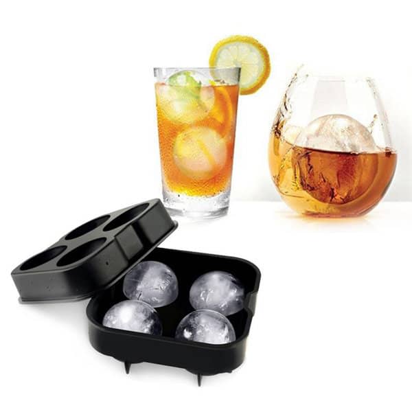 A black silicone ice cube tray with four compartments, next to two glasses of drinks featuring large ice cubes. 4 Holes Silicone Ice Cube Tray - Image 1