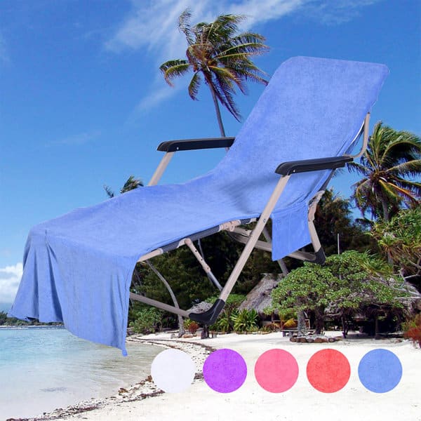A blue microfiber beach chair cover drapes over a lounge chair beside a tropical beach with palm trees. Microfiber Beach Chair Cover - Image 1