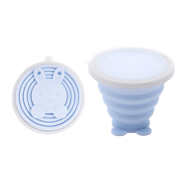 A collapsible silicone travel cup in light blue featuring a bunny design, with a smooth, round lid. It has a logo. Promo Collapsible Silicone Travel Cup - Image 1