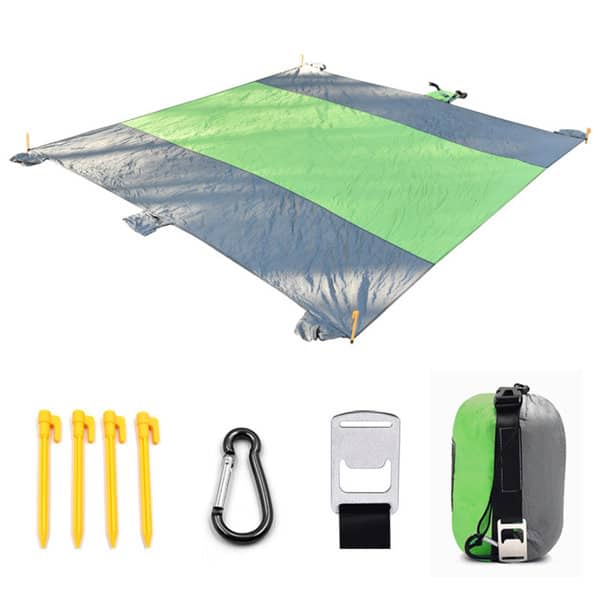 A waterproof picnic blanket in green and grey, accompanied by pegs, a carabiner, and a storage pouch. Waterproof Beach Picnic Blanket - Image 1