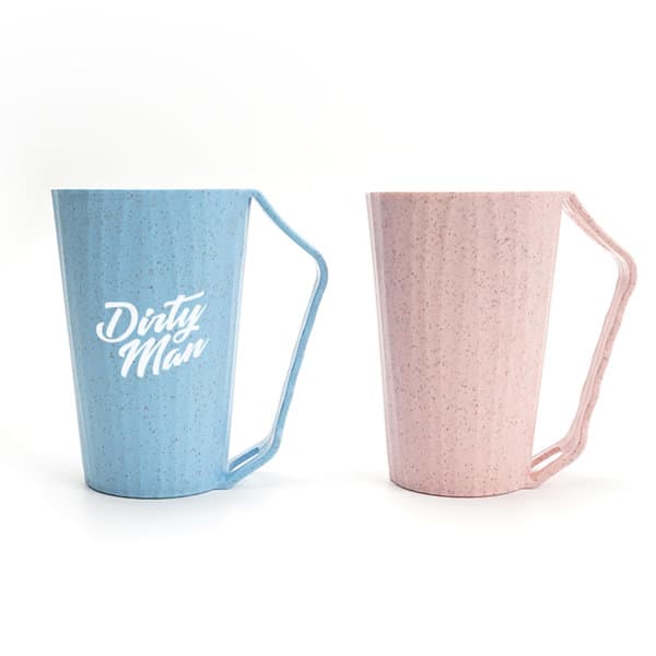 A blue and pink wheat fiber mouthwash cup with a slot handle, featuring a logo on the blue cup. Wheat Fiber Mouthwash Cup With Slot Handle - Image 1