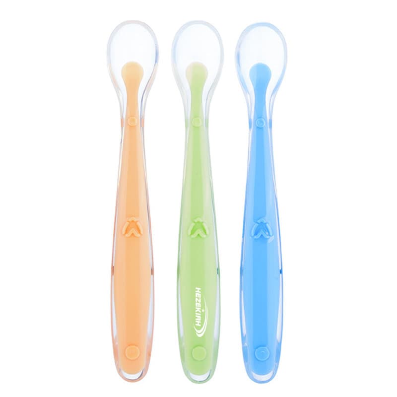 Three soft silicone baby spoons in orange, green, and blue, displayed together with a transparent storage box. Baby Silicone Soft Spoon With Storage Box - Image 1