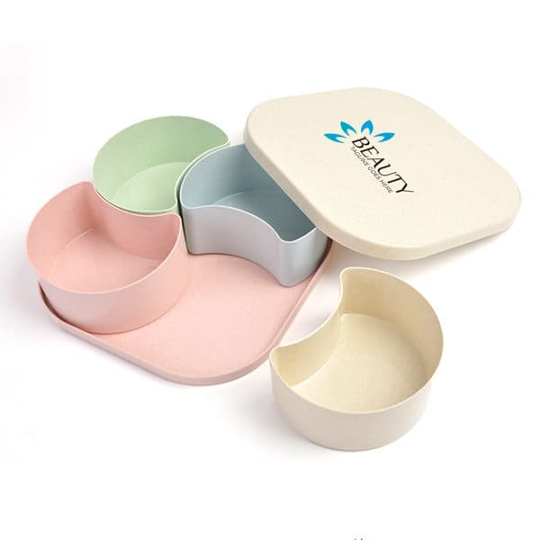 A four-compartment snack tray in pastel colours with a fitted lid, featuring a brand logo. 4 Compartment Wheat Straw Nut Snack Tray With Lid - Image 1