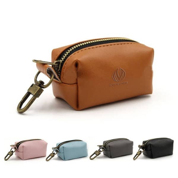 A PU leather dog poop bag holder in brown, featuring a zipper and metal clip, accompanies other colour options in pink, blue, and black. PU Leather Dog Poop Bag Holder - Image 1