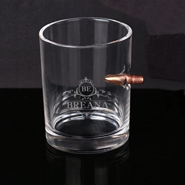 A clear whisky glass featuring a copper bullet design and a logo etched on the side. Bullet Whisky Glass - Image 1