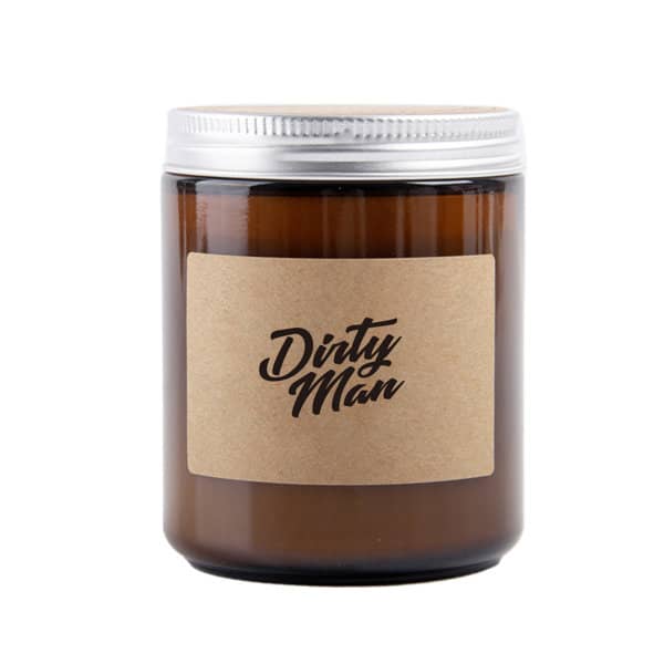 A soy wax scented candle in a dark amber jar with a silver lid and a natural paper label featuring the text "Dirty Man." Soy Wax Scented Candle With Lid - Image 1