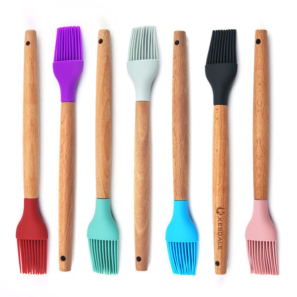 A set of silicone basting brushes in various colours, featuring wooden handles and a brand logo on one brush. BBQ Silicone Basting Brush - Image 1