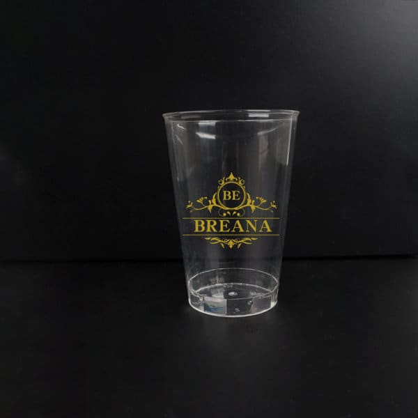 A clear 12 oz. eco-friendly RPET plastic cup with a gold logo design. 12 oz. Eco-friendly RPET Plastic Cup - Image 1