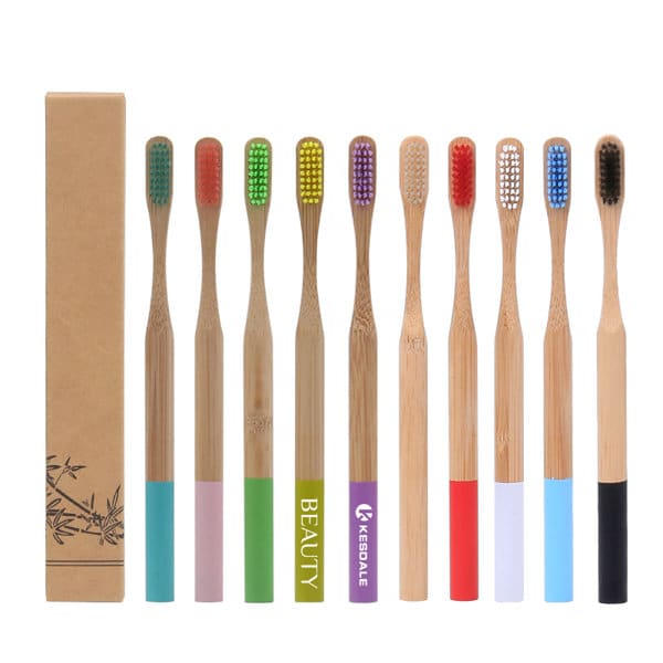 A set of eco-friendly bamboo toothbrushes in various colours, displayed alongside a cardboard box with a logo. Eco Friendly Bamboo Toothbrush - Image 1