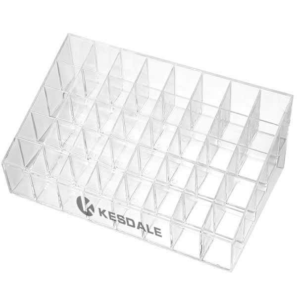 A clear acrylic cosmetics display stand featuring multiple compartments for organisation. It has a logo on the front. Clear Acrylic Cosmetics Display Stand - Image 1
