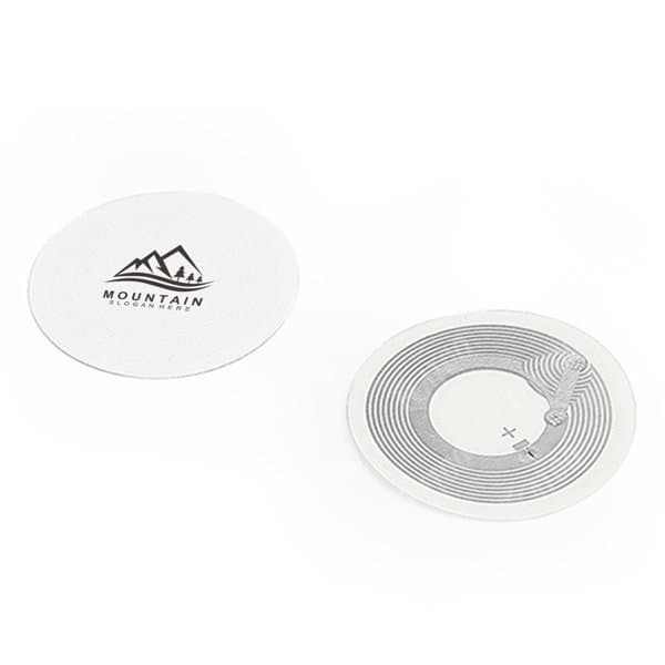 A round, white custom NFC tag sticker with a mountain logo and a circuit design on one side. Custom NFC Tag Sticker - Image 1