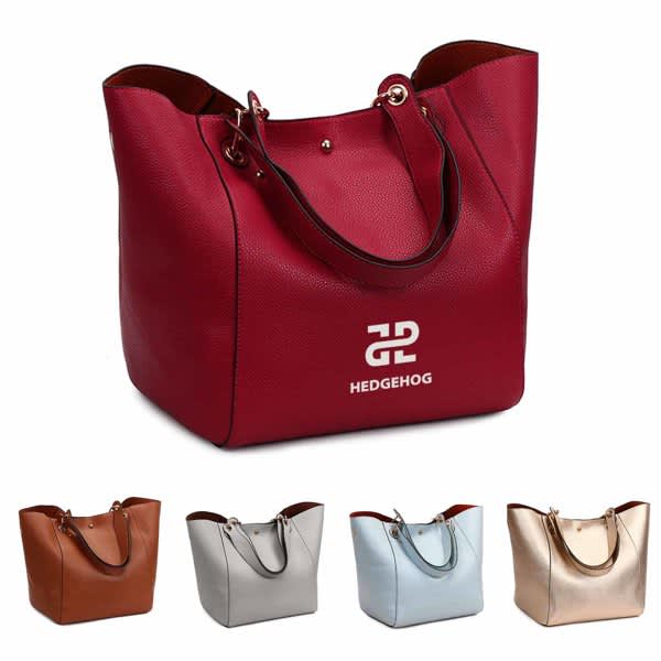A red PU handbag with handles and a logo, alongside three other handbags in brown, silver, and gold. PU Fashionable Handbag - Image 1