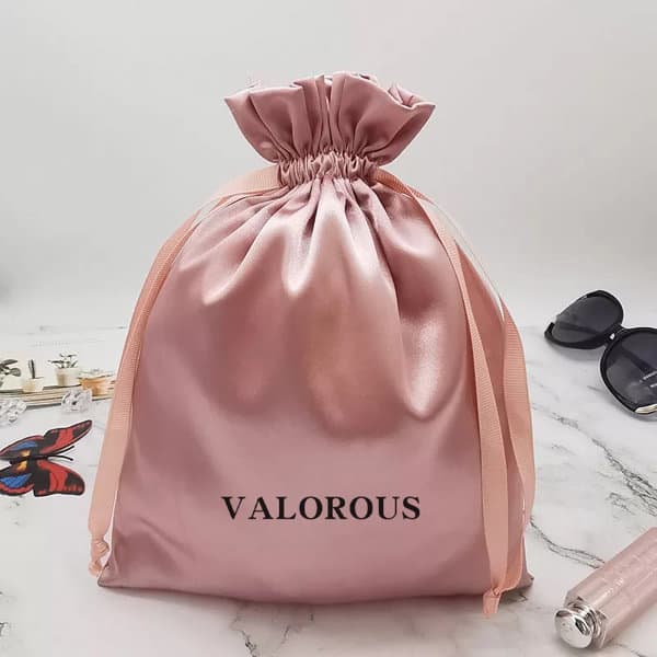 A satin pink drawstring gift bag with a gathered top and ribbon ties, featuring a logo. Satin Gift Bag With Drawstring - Image 1