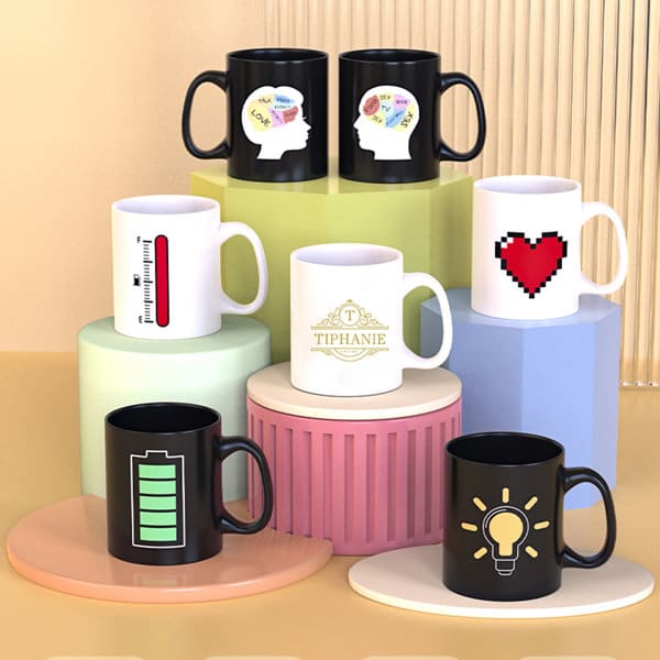 A collection of black and white ceramic mugs displayed on multi-coloured pedestals. Each mug features unique designs and logos. Color Changing Heat Sensitive Ceramic Mug - Image 1