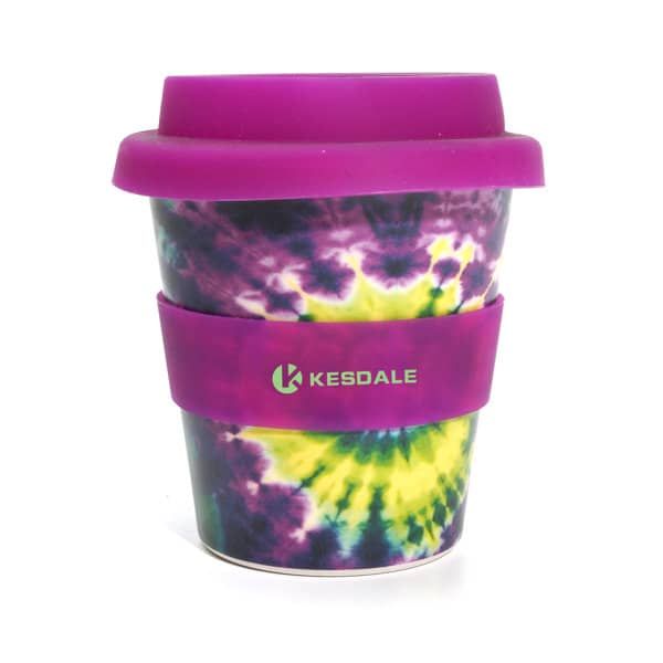 A coffee cup with a tie-dye pattern in purple, yellow, and green, featuring a purple lid and sleeve, with a logo. 4 oz. Coffee Cup With Lid And Sleeve - Image 1