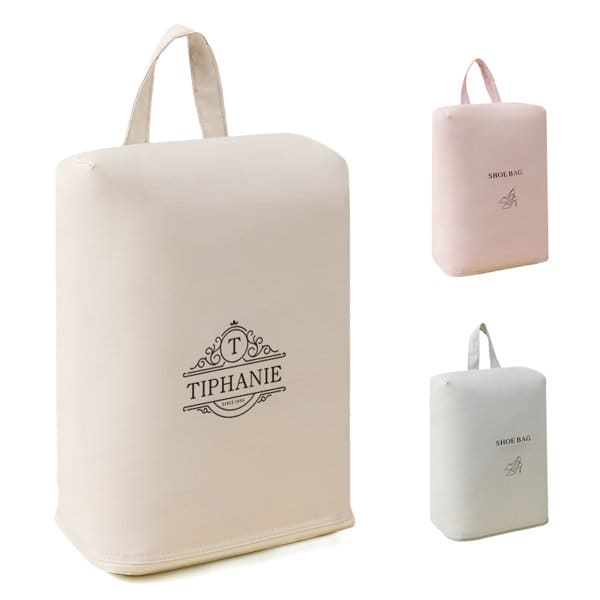 A beige travel shoe storage bag with a handle, featuring a branding logo, alongside pink and white versions. Travel Shoe Storage Bag With Handle - Image 1