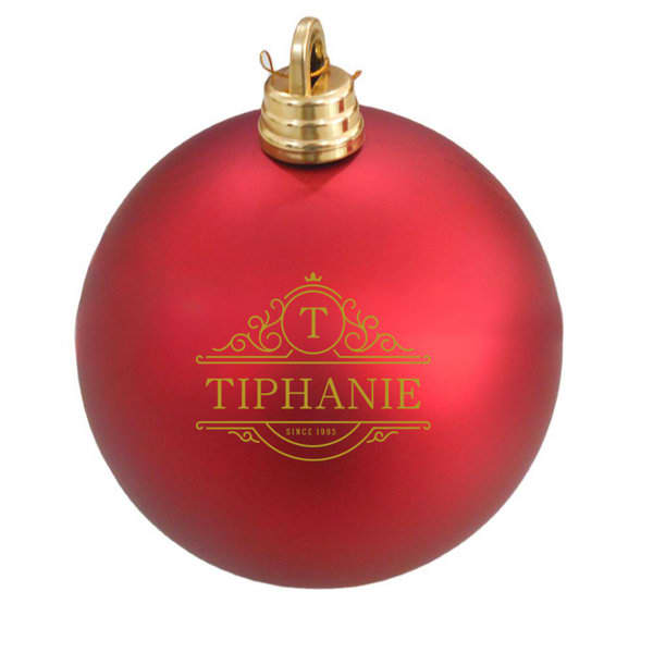 A shiny red Christmas tree ball with a gold decorative logo and a golden top attachment. Christmas Tree Ball - Image 1