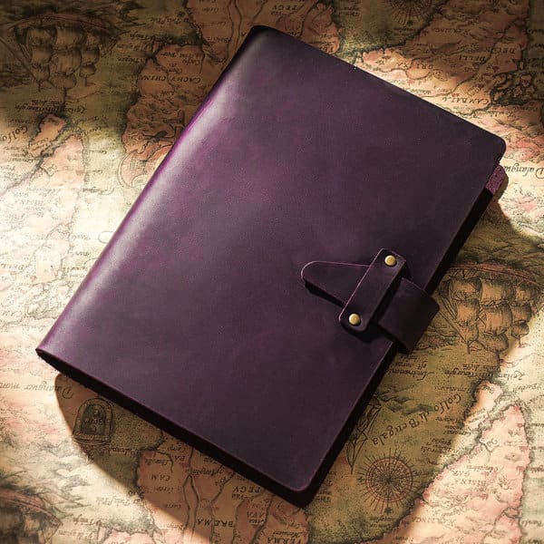 A purple vintage spiral notebook with a buckle closure, resting on an old map background. The notebook has a smooth finish. PU Vintage Spiral Notebook With Buckle - Image 1