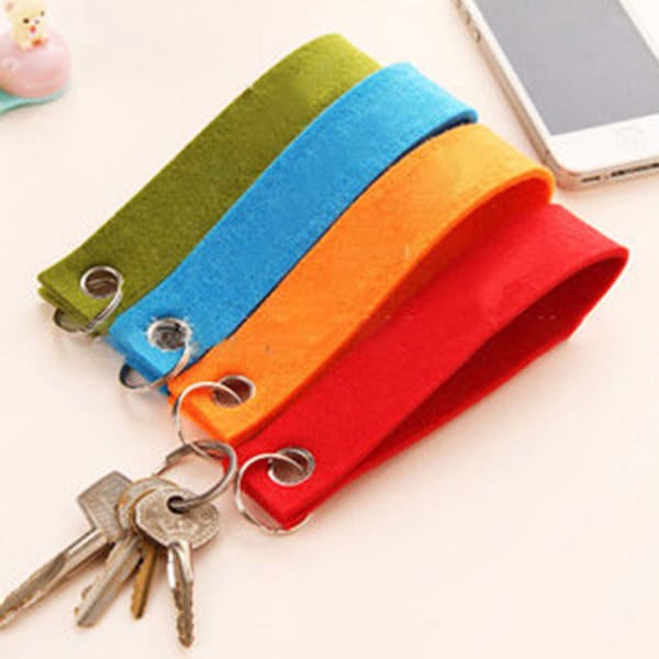 A set of four custom felt key chains in green, blue, orange, and red, attached to metal key rings. Custom Felt Key Chain - Image 1